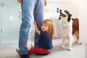 Little girl clutching father's legs